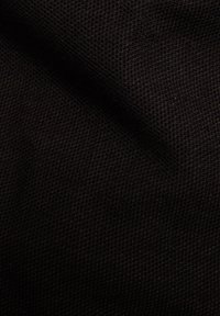 Svart texturerat tyg med ett meshnätmönster, som uppvisar en vävd, något elastisk kvalitet. Ytan är slät med subtil dimension.