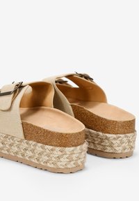 Sandalias de cuña beige con plataforma de corcho, detalle de cuerda texturizada y una correa ancha con hebilla de metal. Plantillas suaves.