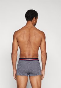 Grå stripete boxershorts med en godt tilpasset design, med en kontrasterende rød og blå linning, sett fra baksiden. Glatt stofftekstur.