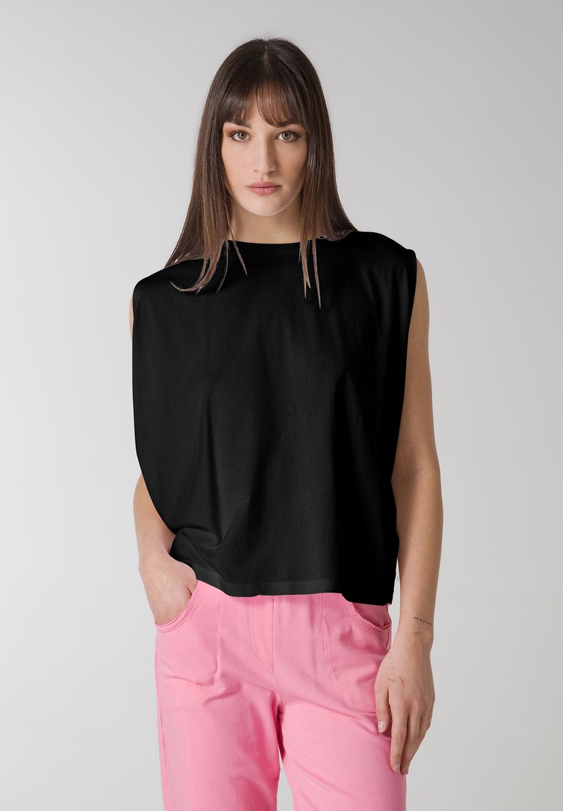 Top nero a maniche corte con una vestibilità ampia e una texture morbida. Abbinato a pantaloni rosa con tasche frontali e un design casual.