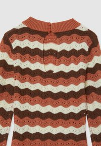 Maglione lavorato a maglia con un motivo a strisce ondulate nei colori ruggine, crema e marrone. Dettaglio con schiena aperta e chiusura a bottone sul collo.