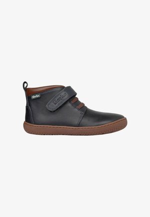 Zapato infantil de cuero negro con suela marrón, cuello marrón y tira de Velcro etiquetada "Gorila."