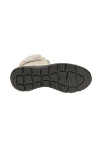 Suela de zapato con un material de goma negro, que presenta un diseño de banda de rodadura para tracción. El zapato tiene una parte superior color crema con forro suave y acentos.