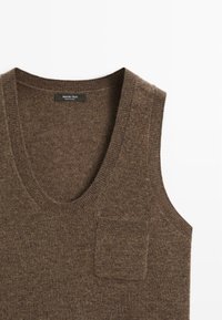 Brun ull ärmlös tröja med djup V-ringning och en liten ficka framtill; mjuk textur, ribbade kanter. Varumärkesetikett inkluderad.