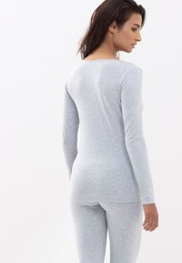 Jasnoszary, długi rękaw top wykonany z miękkiego, elastycznego materiału. Dopasowany krój z okrągłym dekoltem, w komplecie z dopasowanymi legginsami.