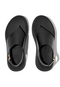 Sandales noires au design épuré, fabriquées en matériau synthétique lisse, avec une semelle plate et un accent doré sur la bride.