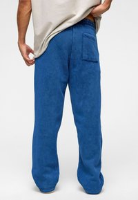 Blauwe joggingbroek van zacht materiaal, met een achterzak, een relaxte pasvorm en een elastische tailleband met een textuuraccent.