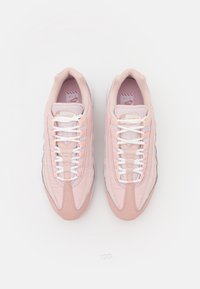 Ljusrosa sneakers med en texturerad ovandel, vita skosnören och en slank design. Har accentdetaljer i mörkare rosa och reflekterande silver.