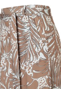 High-waist beige skirt with white and brown tropical leaf patterns and a fabric belt tied at the waist.
