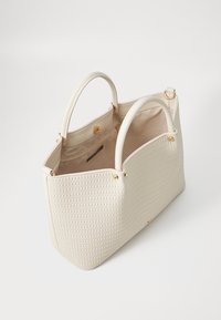 Beżowa tkana torba na ramię z gładkimi uchwytami ze sztucznej skóry. Wnętrze posiada przestronną przegrodę i zapięcie na magnes. Złote ozdobne elementy metalowe.