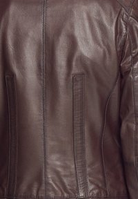 Braune Lederjacke mit glatter Textur, ausgestattet mit zwei vertikalen Seitentaschen und kontrastierenden Nähten entlang der Säume.