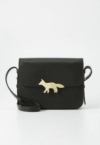 Črna usnjena torbica čez telo z zlatim zaponkom v obliki lisice na sprednji strani, pravokotne oblike in nastavljivim trakom. Gladek pridih.