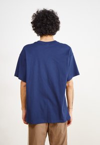 T-shirt en coton bleu marine avec une coupe décontractée, col rond, manches courtes et une texture lisse ; vu de dos.