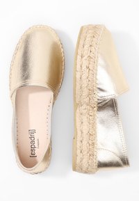 Espadrillas slip-on in oro metallizzato con suola in juta intrecciata. Texture liscia, punta rotonda e design aperto sul retro. Logo del brand visibile all'interno.