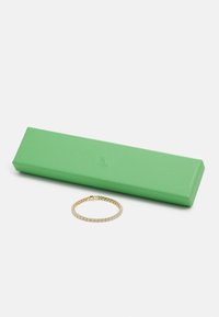 Caixa de joias retangular verde com acabamento texturizado ao lado de uma pulseira dourada com uma série de strass transparentes em uma corrente ligada.