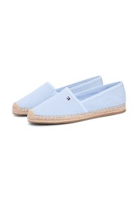 Espadrilles en toile bleu clair avec semelles en jute, présentant une texture tissée et un accent logo sur un côté. Design bas et facile à enfiler.