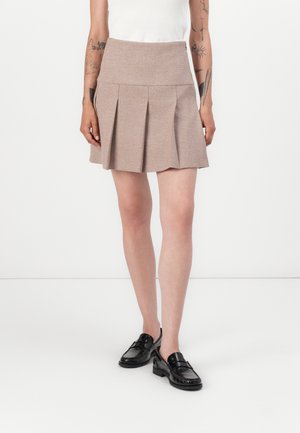 Brown, pleated skirt with a high waistband, made from textured fabric. Paired with black loafers, featuring a smooth finish.