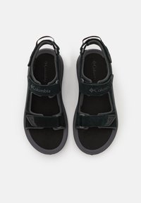 Las sandalias negras cuentan con una parte superior de textil con correas ajustables, plantilla acolchada, suela de goma y un destacado detalle de logo.