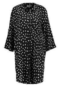 Schwarzes Hemd mit weißen Polka-Dots, mit Knopfleiste, Kragen, Dreiviertelärmeln und aufgesetzter Tasche. Aus leichtem Stoff gefertigt.