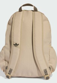 Beżowy plecak wykonany z trwałej tkaniny, wyposażony w dwie boczne kieszenie, regulowane paski oraz czarny akcent z logo na przedzie.