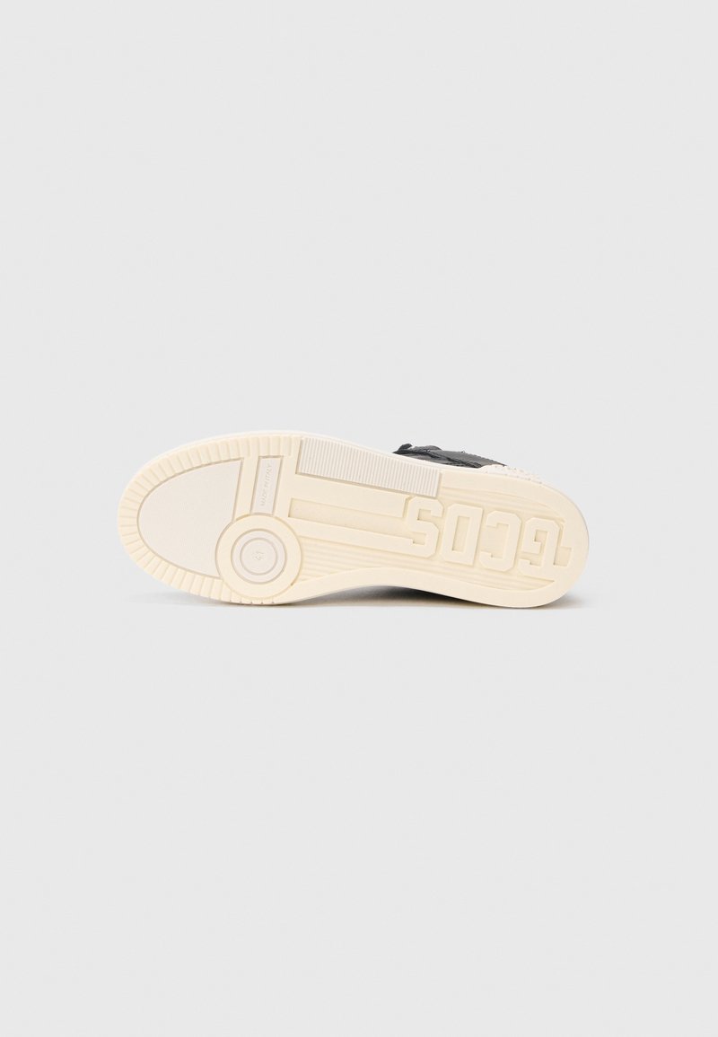Black sneaker with a textured upper and white rubber sole, featuring a visible logo on the side and a patterned tread for traction.