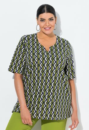 Chemise à manches courtes en motif vagues bleu marine, vert et blanc, avec un col en V et une coupe décontractée, accompagnée d'un pantalon vert.