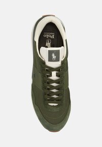 Zapatilla deportiva verde con parte superior de malla y ante, cordones blancos, suela de goma y un pequeño logo en la lengüeta y el lateral.