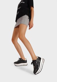 Sneakers platform nere con tomaia in pelle liscia, dettagli argentati sul tallone e suola bianca in contrasto. I lacci sono neri con dettagli di branding.