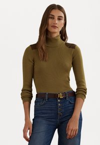 Pull en maille côtelée vert olive avec des accents bruns sur les épaules, associé à un jean taille haute bleu foncé et une ceinture brune ornée d'un logo doré.