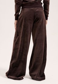 Brown, wide-leg pants made of soft velour fabric. Features a high waistband and smooth texture, tailored for comfort and ease of movement.