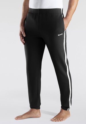 Schwarze Jogginghosen mit weißen seitlichen Streifen, elastischem Bund und gerippten Bündchen. Der Stoff wirkt glatt und leicht mit einem Logo auf der Vorderseite.