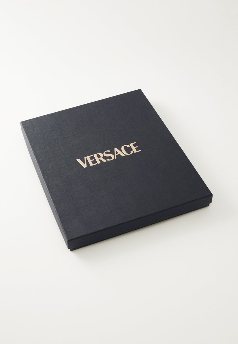 Scatola blu navy con superficie texturizzata, con la scritta dorata in rilievo "VERSACE" sulla parte superiore. Chiusa, di forma quadrata.