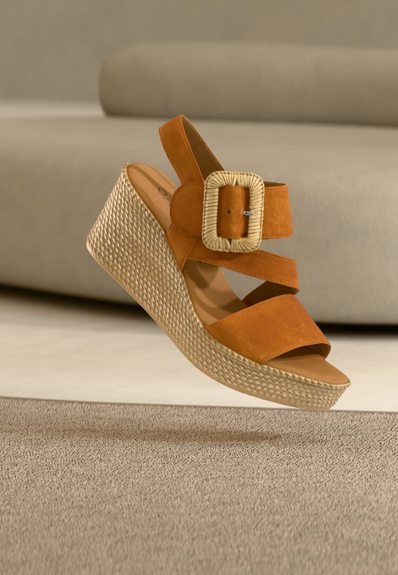 Sandale compensée en daim marron avec une plateforme en corde tressée, deux brides croisées et un grand détail de boucle tressée.