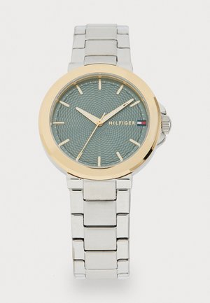 Silver stainless steel watch with a textured mint green face, gold-tone bezel, and gold hands. Features a link bracelet strap.