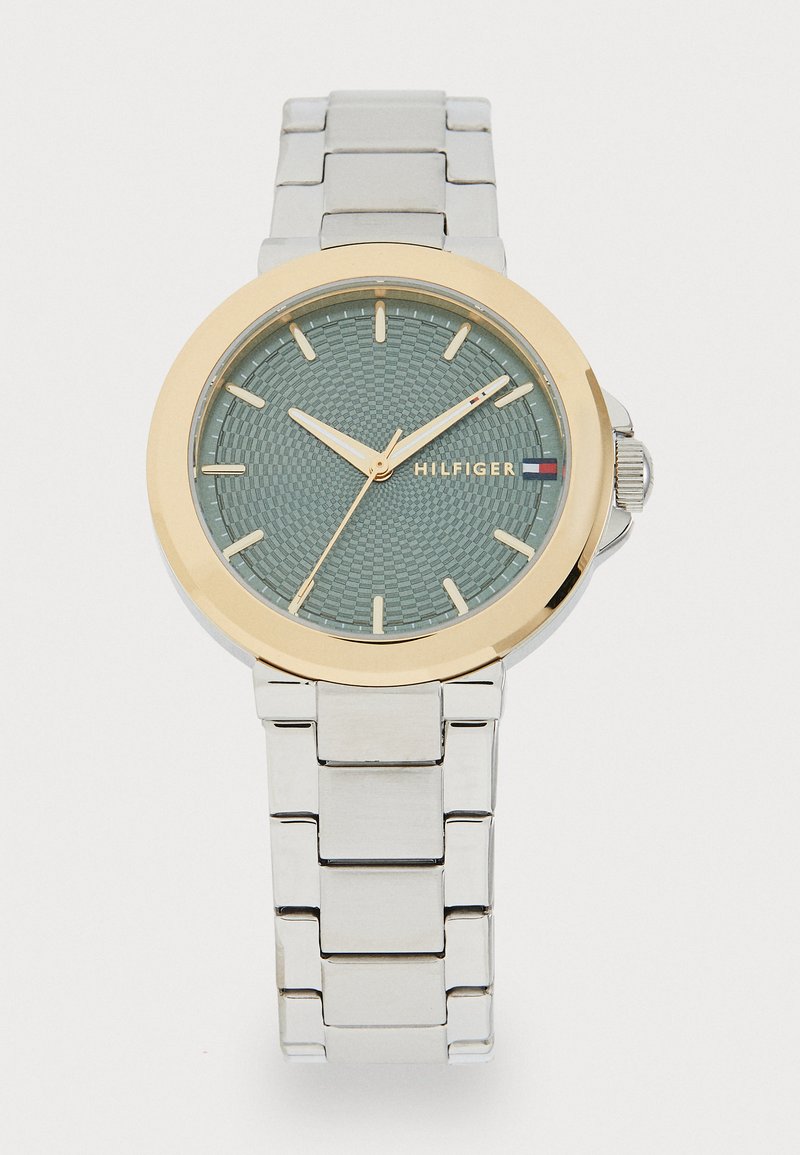 Silver stainless steel watch with a textured mint green face, gold-tone bezel, and gold hands. Features a link bracelet strap.