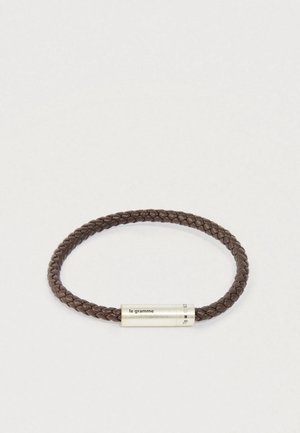 Punutud tumepruun nahkne käevõru, millel on silindrikujuline hõbedane lukk, millel on graveeritud "le gramme" ja kaalu andmed.