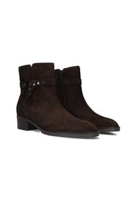 Bottines en suède marron avec un bout arrondi, une fermeture éclair sur le côté et une sangle décorative avec des accents en métal sur la tige. Talon bloc bas.