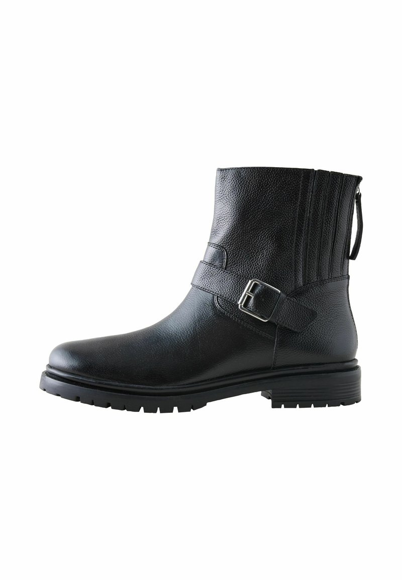 Bota corta de cuero negra con superficie texturizada, correa ajustable y detalle de hebilla, acentos cosidos, punta redondeada y suela de goma.