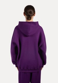 Sudadera morada de gran tamaño con una gran capucha, fabricada en un tejido suave; puños y dobladillo acanalados, textura lisa y corte relajado.