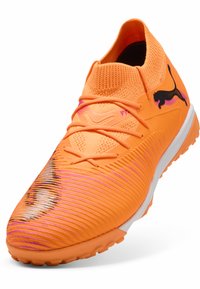 Orange sportssko med et tekstureret design, der har en vævet overdel, markante snørebånd og et sort logo på siden.