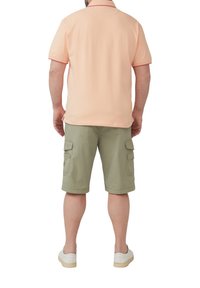 Hellrosa Polo-Shirt mit kurzen Ärmeln und rotem Rand, kombiniert mit olivgrünen Cargo-Shorts mit Seitentaschen und umgeschlagenem Saum.