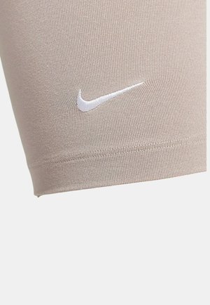 Shorts de sport beiges en tissu extensible, ornés d'un logo Nike blanc. Design ajusté avec une texture lisse et des coutures soignées.