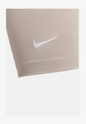 Shorts de sport beiges en tissu extensible, ornés d'un logo Nike blanc. Design ajusté avec une texture lisse et des coutures soignées.