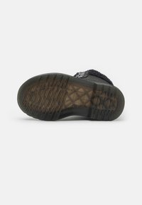 Talpa de pantof negru din cauciuc texturat, având rigle orizontale și verticale pentru aderență. Secțiuni clare din plastic dezvăluie materialele de bază.