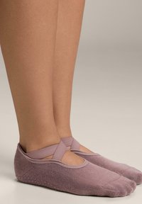 Ljuslila sockor med fotfäste och ett korsat remdesign vid anklarna, tillverkade av mjukt material och med en strukturerad yta.