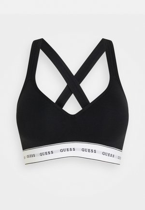 Black bra with a v-neck design, featuring crisscross straps and a white band printed with "GUESS" around the bottom. Soft material, seamless.