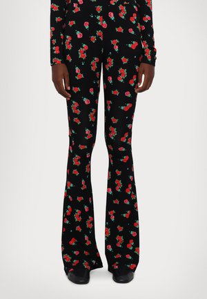 Flared pants in a black fabric adorned with red and green floral patterns. Features tailored fit with smooth texture and subtle sheen.