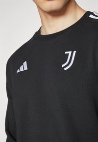 Sort sweatshirt i bomuldsblanding med hvide Adidas-striber på skuldrene og Juventus-logo på brystet. Klassisk crew neck design.