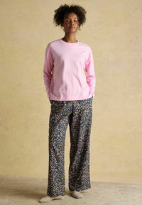 Pink long-sleeve shirt paired with black floral-patterned pants. The fabric is soft; the pants have a relaxed fit and vibrant floral accents.
