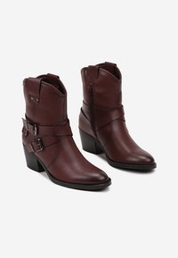 Bottines en cuir bourgogne avec un bout arrondi, fermeture éclair sur le côté et deux sangles décoratives avec boucles. Talon épais pour plus de stabilité.